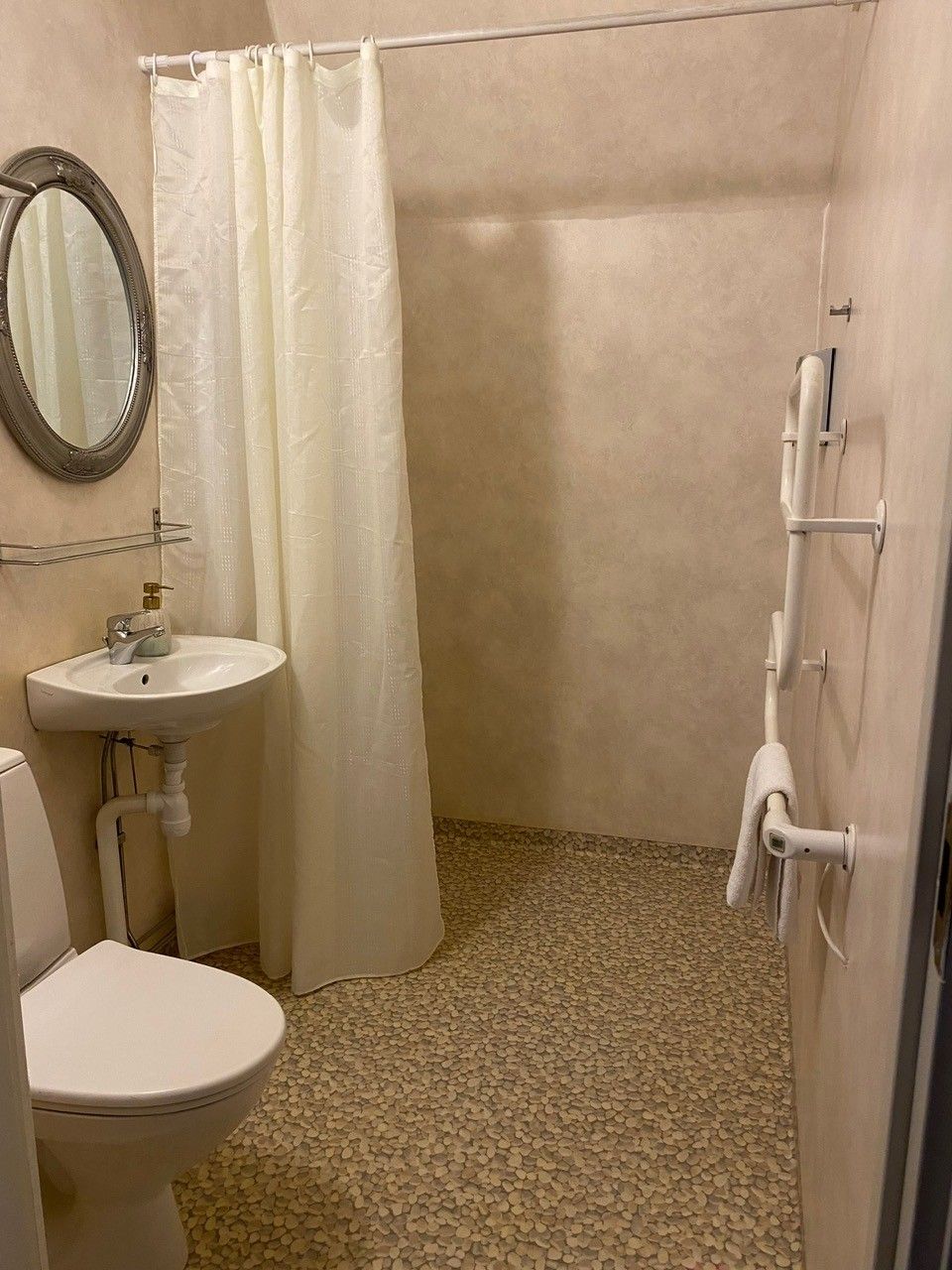 Ein Badezimmer mit Toilette, Waschbecken und Duschbereich.