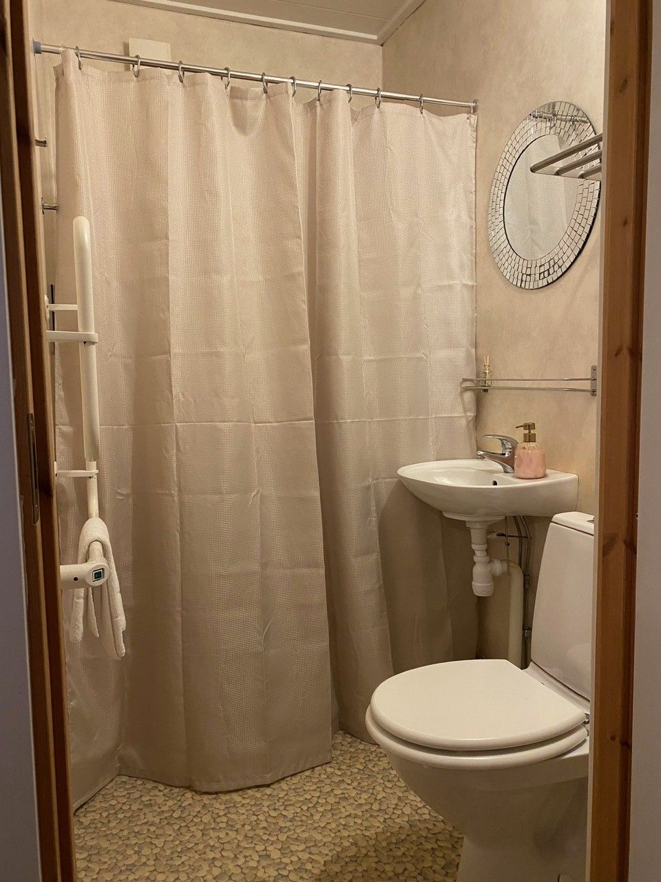 A bathroom with a shower curtain, a toilet, a sink, and a towel rack.