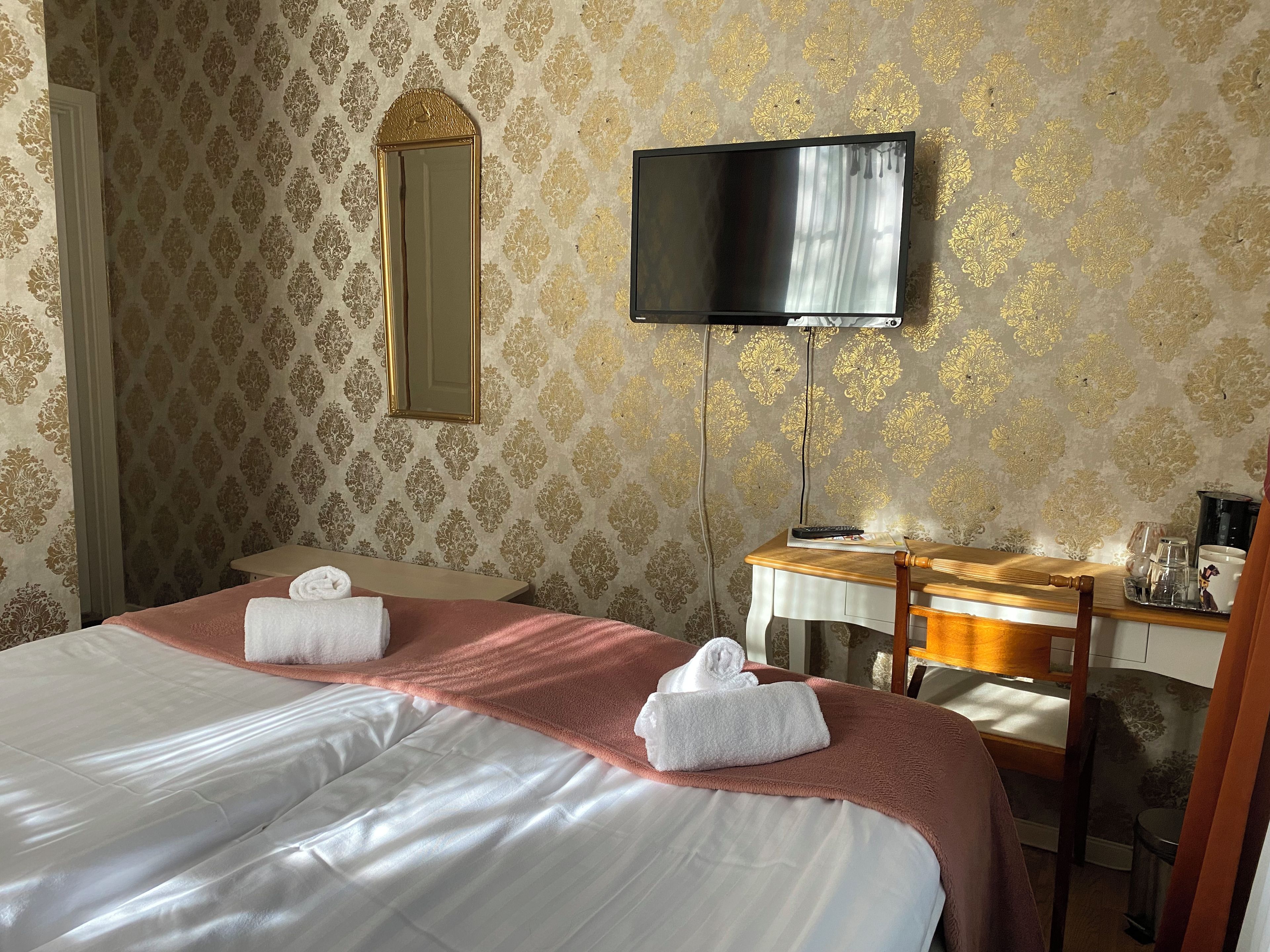A hotel room with a bed, a desk, a television, and a mirror.
