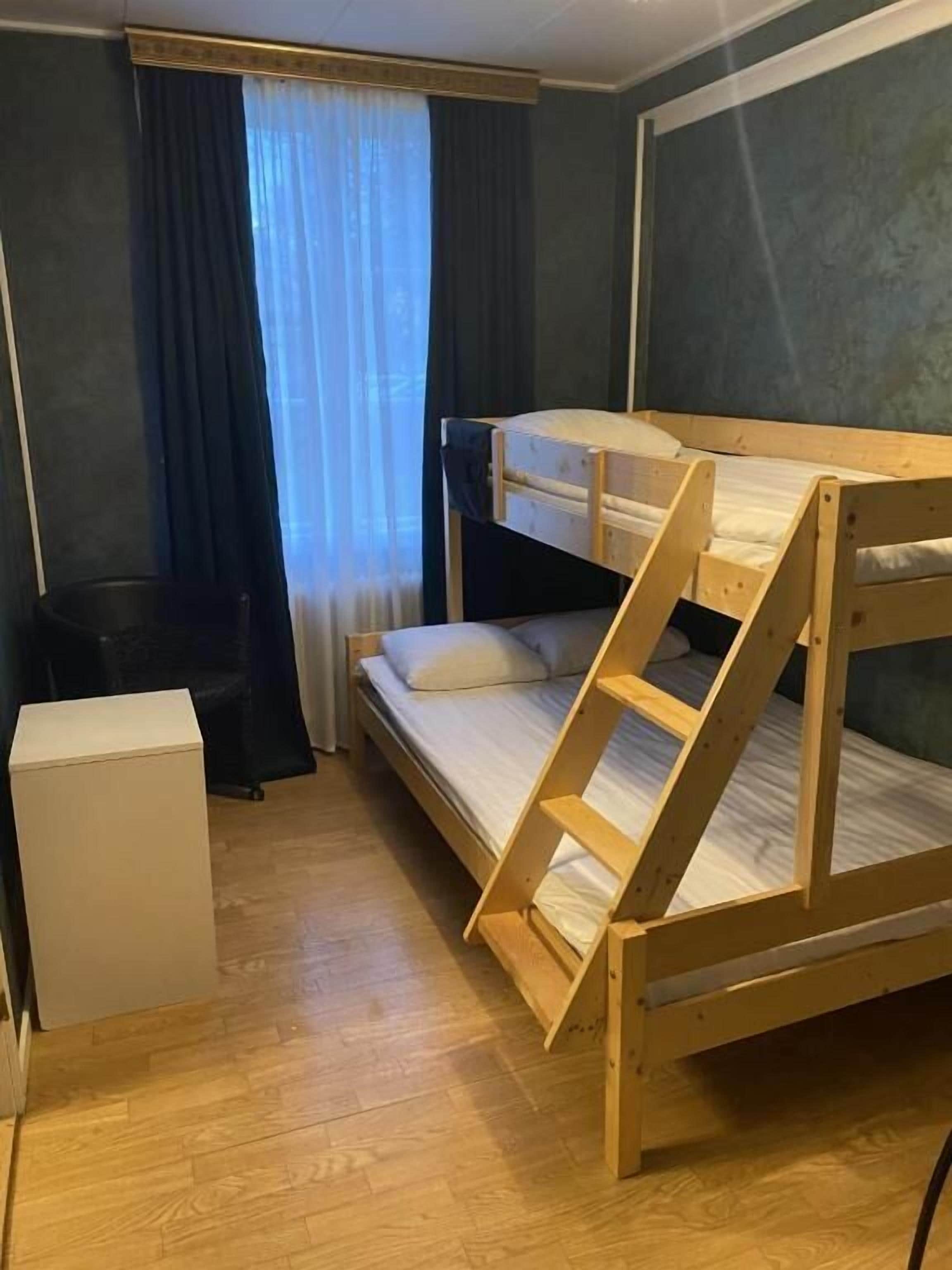 Dormitorio con literas, un escritorio y un mueble auxiliar.