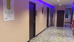 A hotel hallway with patterned flooring, doors, and a sign on the wall. - J P Inn Pattaya Boutique Hotel (Pattaya)