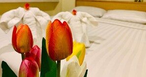 Une chambre d’hôtel avec un lit soigneusement fait et un bouquet de tulipes au premier plan.