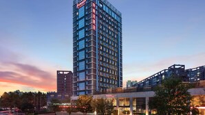 A modern high-rise hotel with multiple floors, large windows, and a prominent entrance area with signage. - Ramada by Wyndham Xi'an Long march (Xi'an)