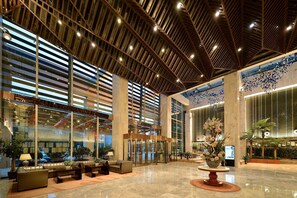 Een ruime lobby met een hoge plafond, grote ramen en een centraal gelegen zithoek.