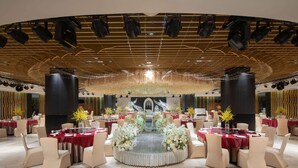 A banquet hall with round tables, a central floral arrangement, and a stage with lighting. - Ramada by Wyndham Xi'an Long march (Xi'an)