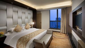 A modern hotel room with a large bed, a sofa, a TV, and a view of the cityscape. - Ramada by Wyndham Xi'an Long march (Xi'an)