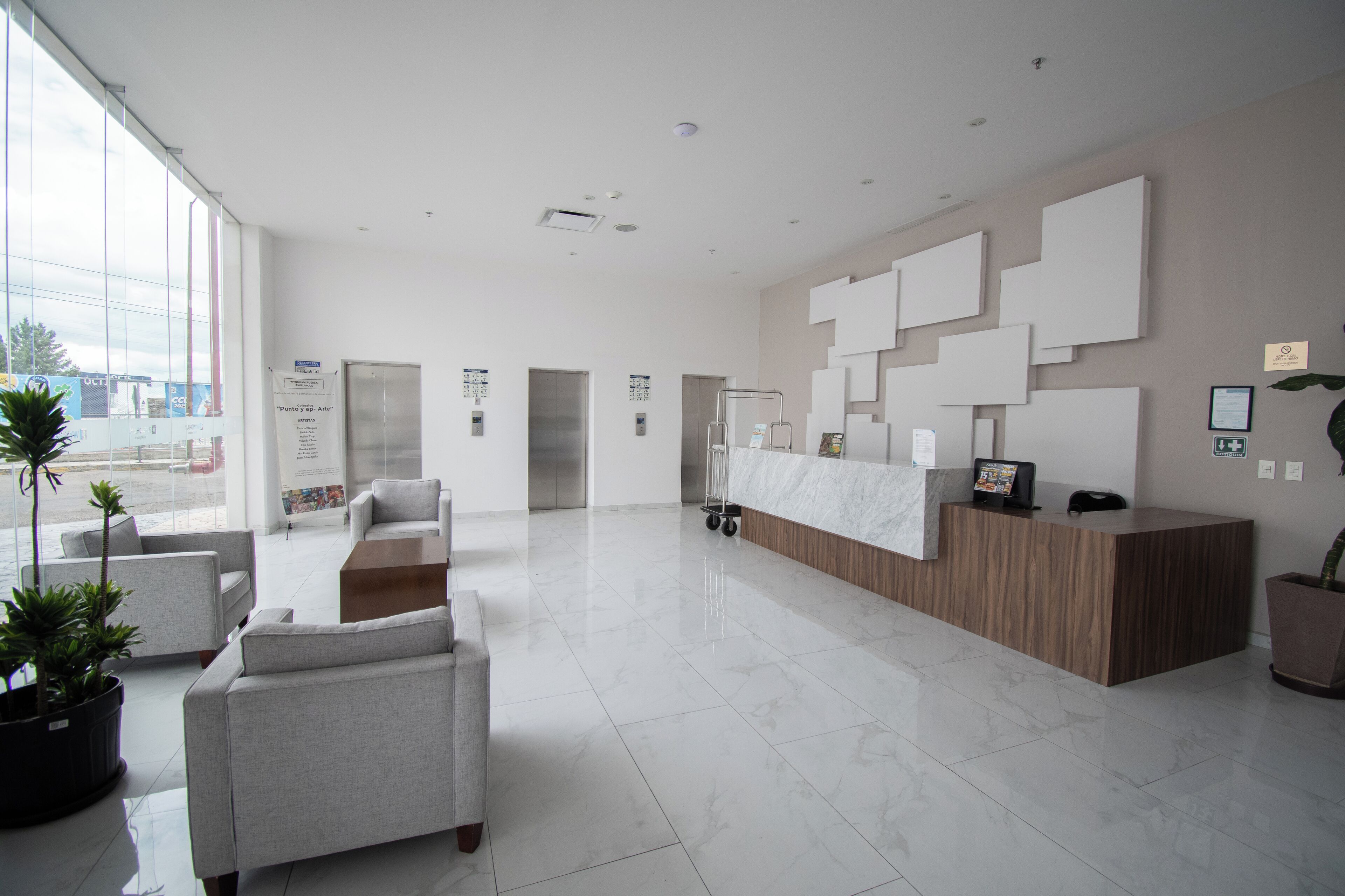 Eine geräumige Lobby mit einer Rezeption, einer Sitzecke und großen Fenstern.