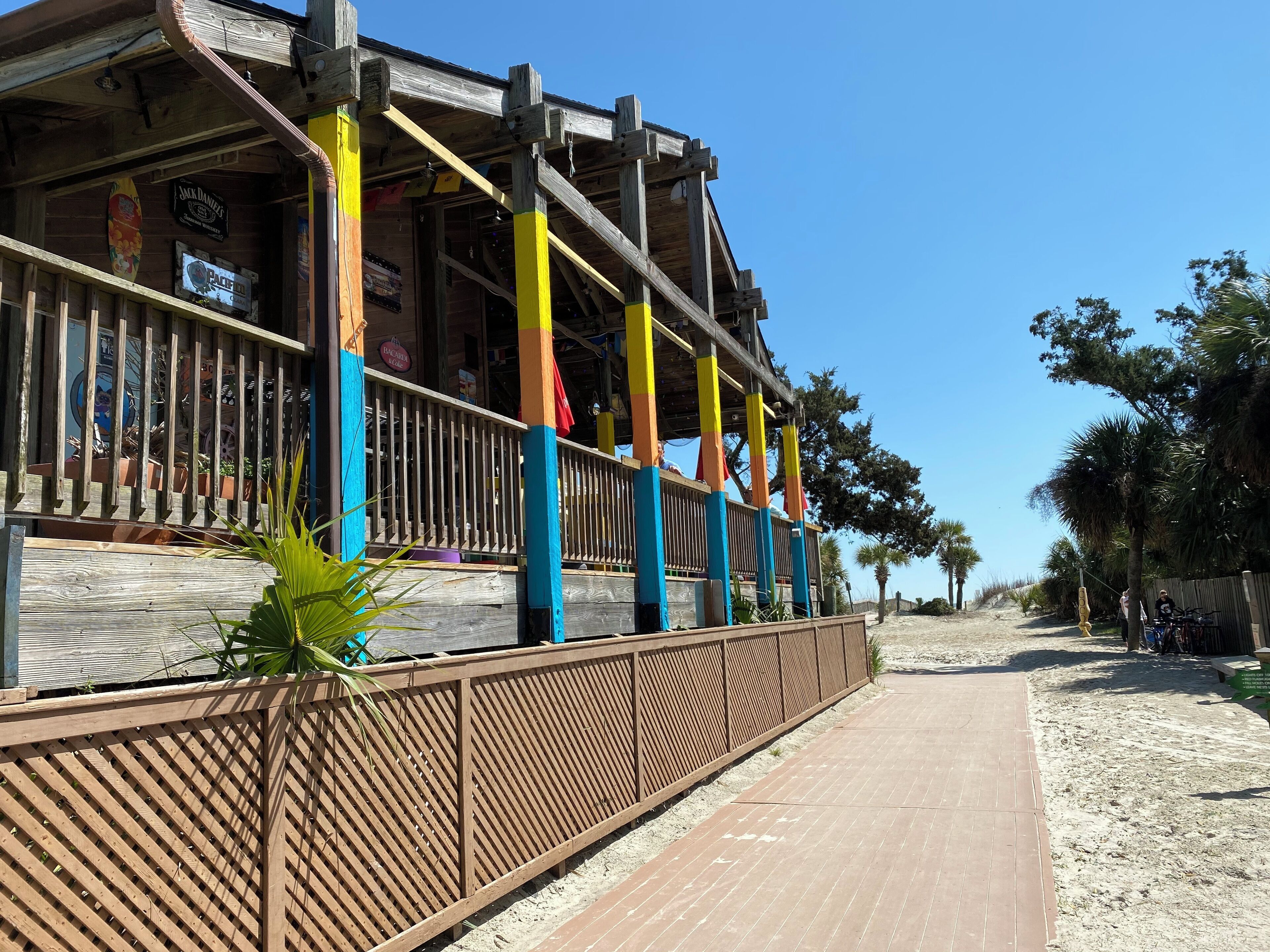 A beachside building with a wooden deck and colorful vertical supports.
