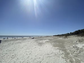 Una playa con cielo despejado y huellas en la arena.
