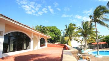 A resort with a swimming pool, palm trees, and a building with arched windows.