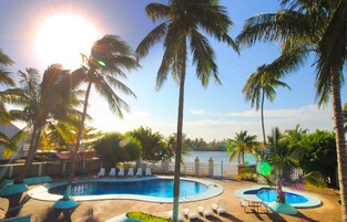 Zona de piscina con varias piscinas, palmeras y vistas al agua.