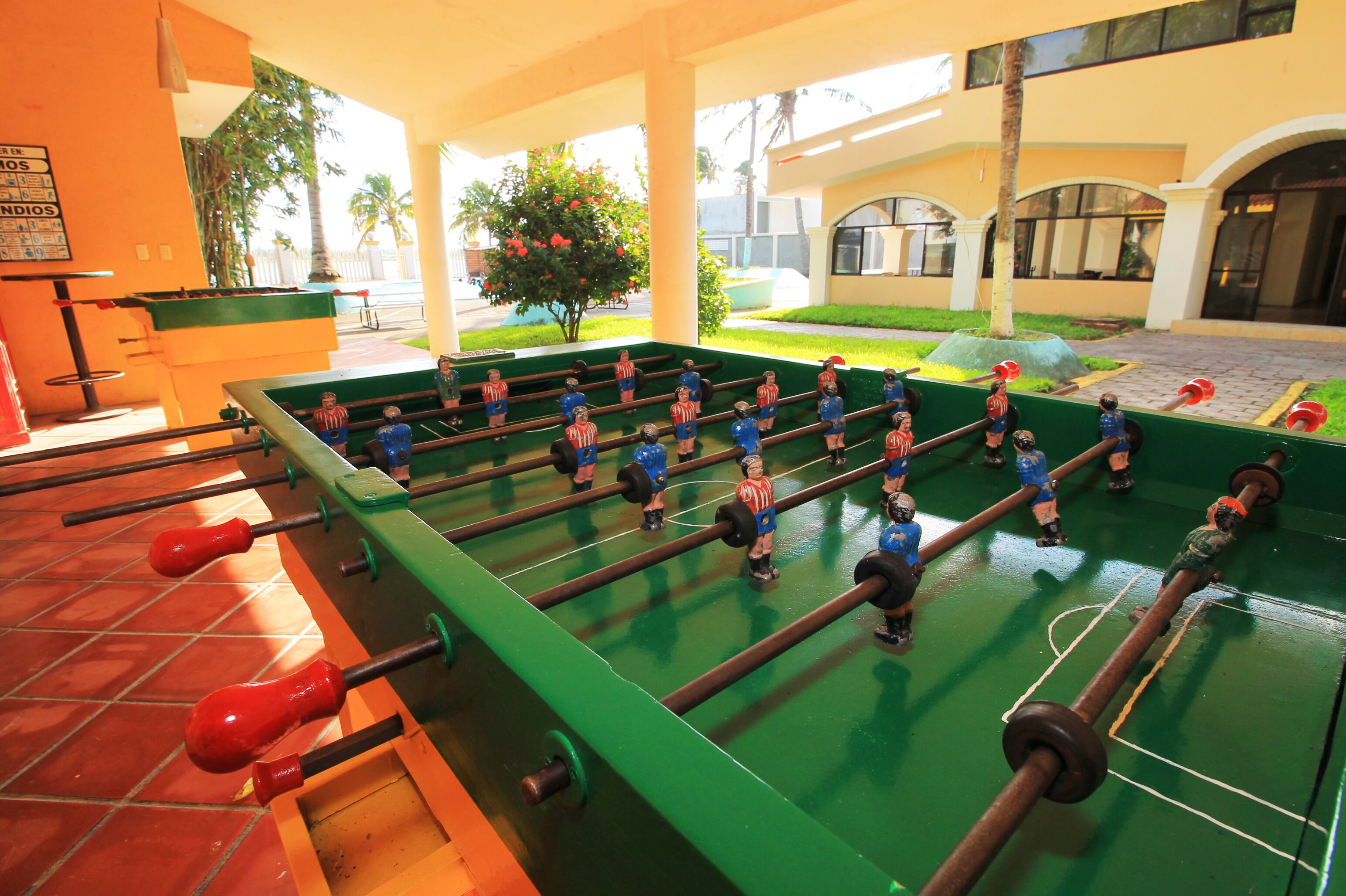 Un tavolo da calcio in un ambiente interno luminoso con pavimento piastrellato e tavolo verde.