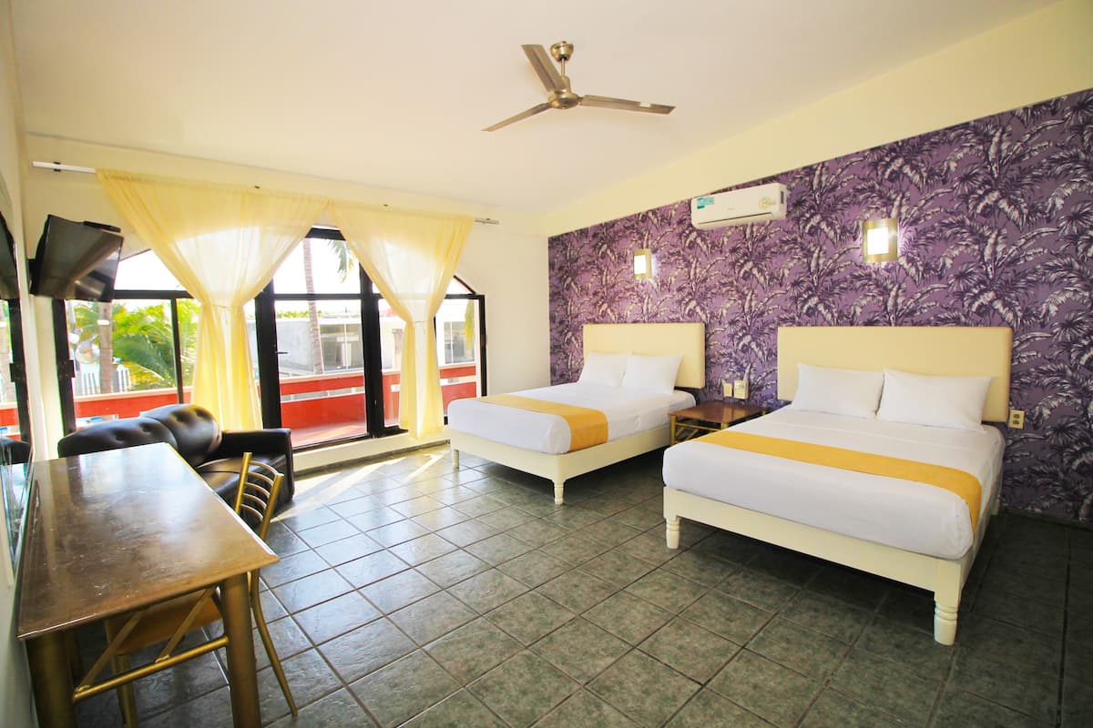 A hotel room with two beds, a dining table, and a TV.