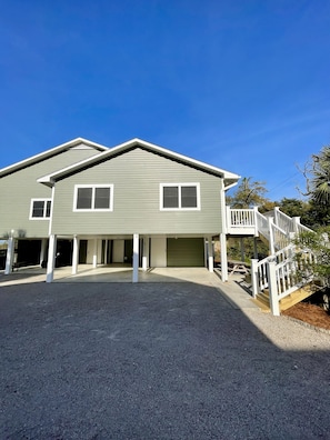 A two-story house with a covered garage, a front porch, and a staircase leading to a deck.
