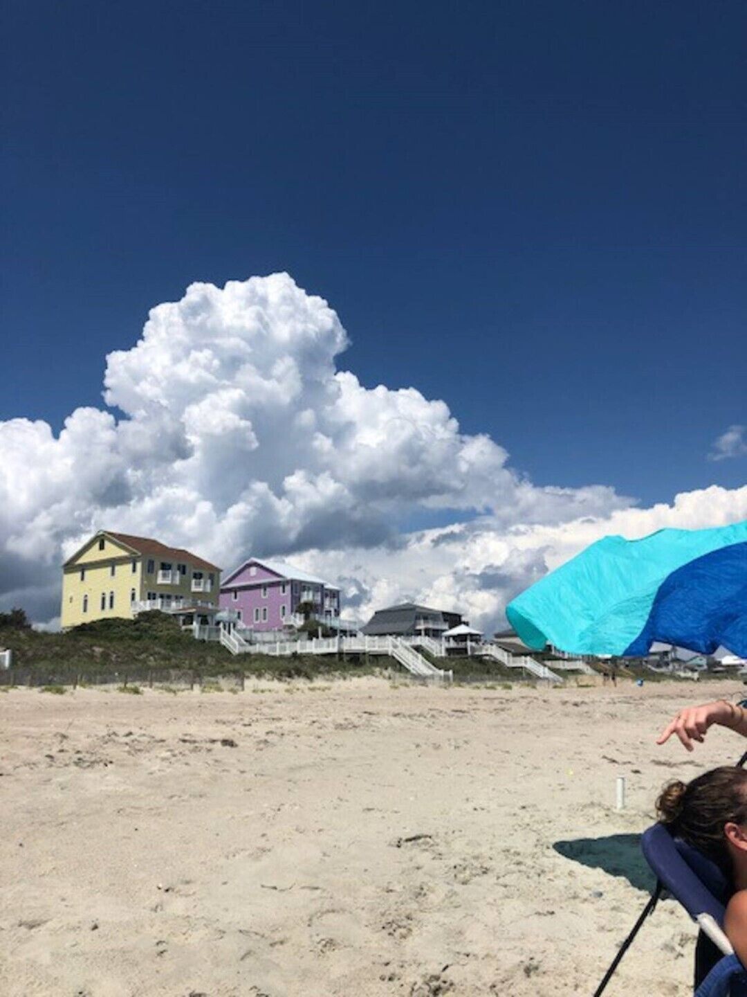 A beach with houses and a large cloud in the sky.
