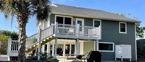 A two-story house with a balcony, a barbecue grill, and a covered patio area.