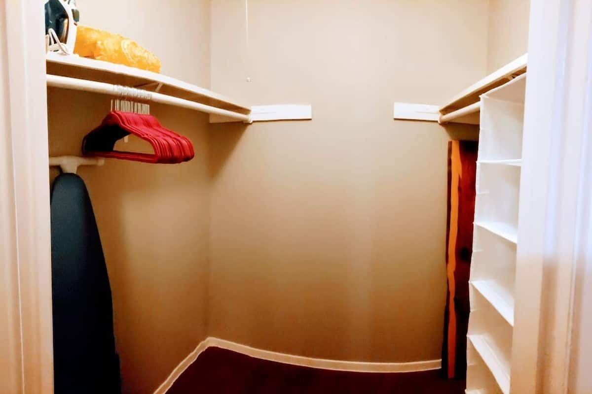 Een kast met planken en een hanggedeelte, een rode kledingstuk en een witte plank met een geel voorwerp.