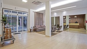 A spacious lobby with a reception desk, seating area, and a luggage cart. - The Hill Executive (São Carlos)