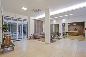 A spacious lobby with a reception desk, seating area, and a luggage cart.
