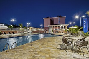 A pool area with lounge chairs and a building with a sign reading "Slaviero Executive".