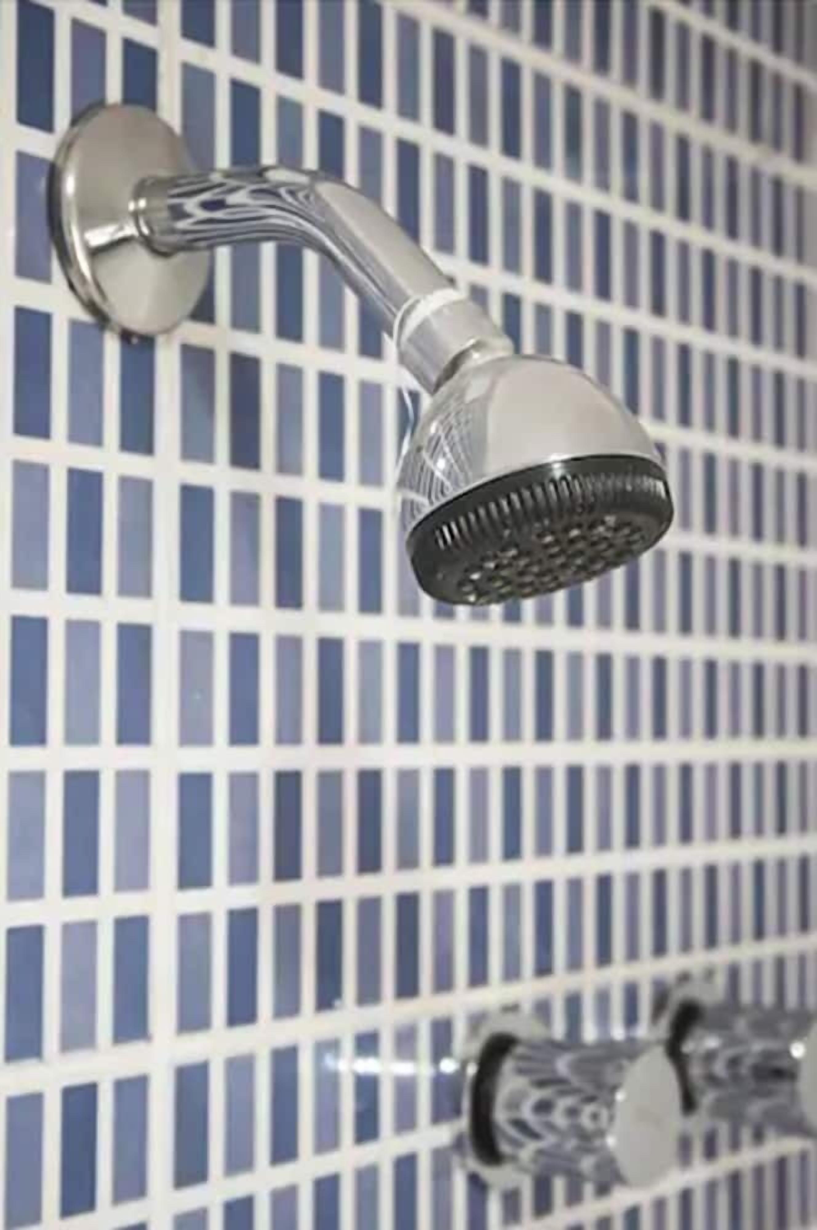 Un cabezal de ducha con diseño curvo, montado en una pared con azulejos de patrón enrejado.