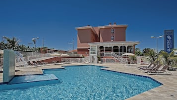 Piscina com espreguiçadeiras e um edifício com a placa 'Slaviero Executive'.