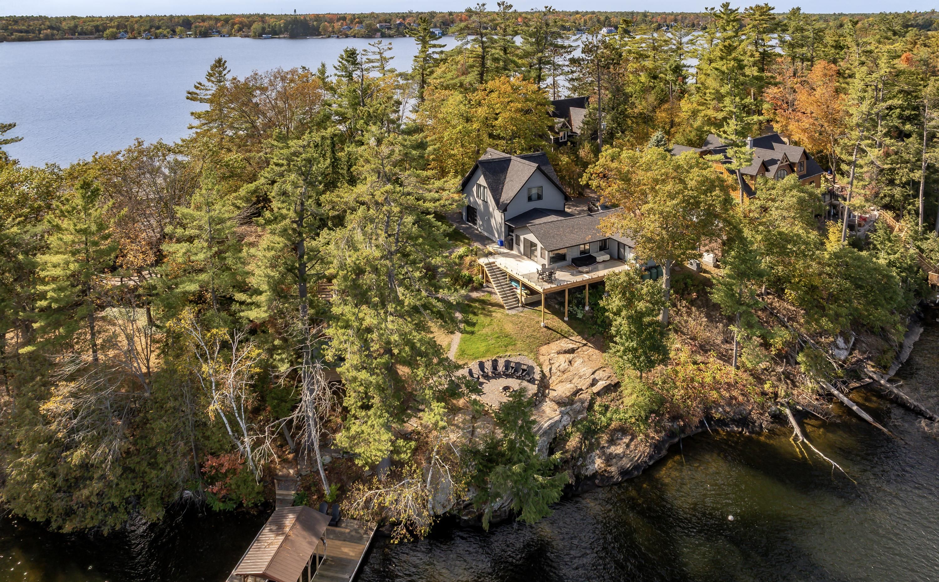 An aerial view of a lakeside property with multiple houses, a dock, and a stone fireplace.
