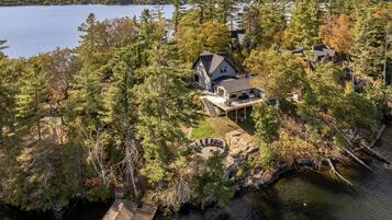 An aerial view of a lakeside property with multiple houses, a dock, and a stone fireplace.