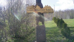 A bear statue with a sign pointing to Green Mountain Cabins and a phone number. - Killington / Rutland 2 bedroom Cabin, Cabin #2 (Mendon)