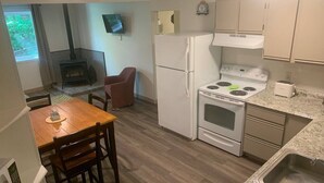 A compact kitchen with a stove, refrigerator, and dining area. - Killington / Rutland 2 bedroom Cabin, Cabin #2 (Mendon)
