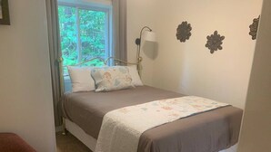 A bedroom with a bed, a chair, a window, and wall decorations. - Killington / Rutland 2 bedroom Cabin, Cabin #2 (Mendon)