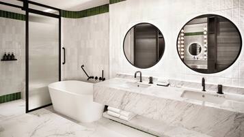Un baño moderno con una bañera independiente, dos lavamanos y dos espejos grandes.