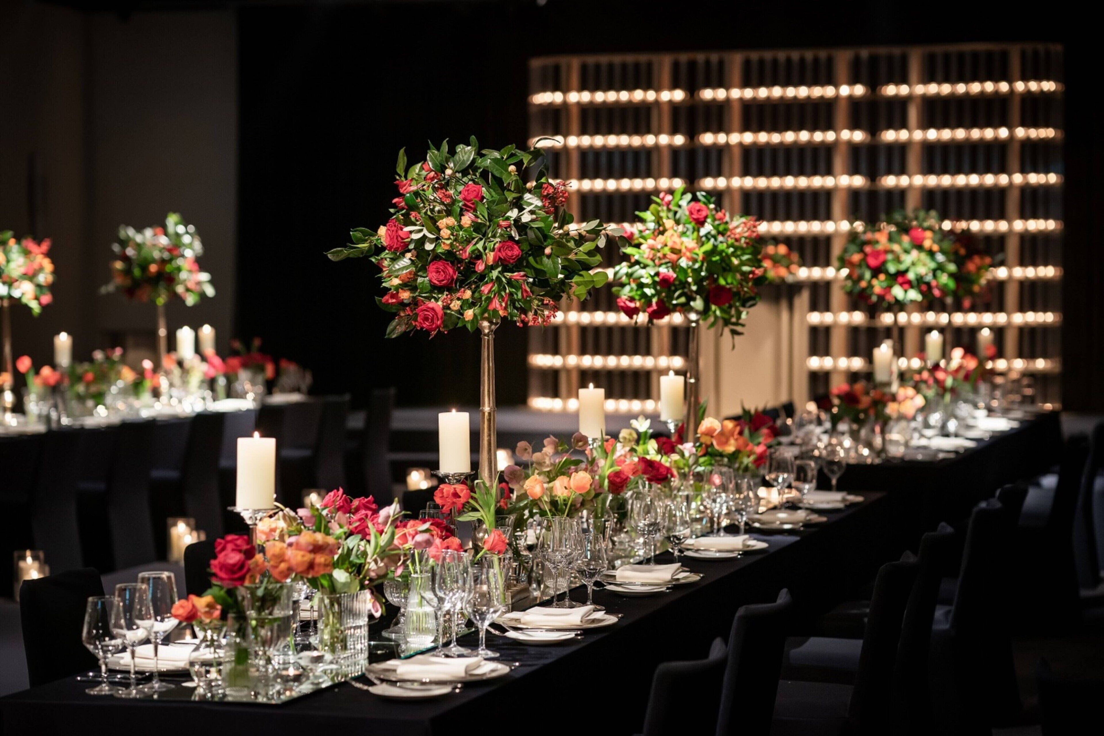 Et langt spisebord dækket med stearinlys, glas og blomsterarrangementer.
