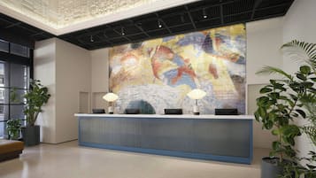 Taulell de recepció amb un mural abstracte i colorit, plantes en testos i un disseny de sostre modern.