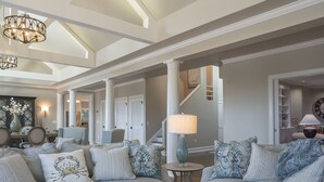 A spacious living room with a high ceiling, a chandelier, and a staircase leading to another level. - Incredible Oceanfront Home-Sleeps 8! Huge Deck! Beach Access! Amenity access included (Seabrook Island)