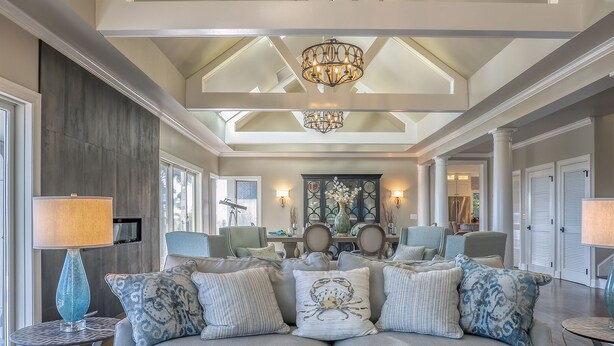 A spacious living room with a high ceiling, a chandelier, and a sofa with multiple cushions. - Incredible Oceanfront Home-Sleeps 8! Huge Deck! Beach Access! Amenity access included (Seabrook Island)