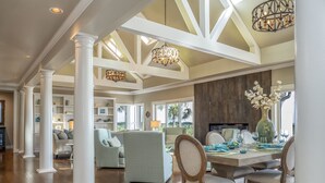 A spacious living area with high ceilings, white columns, and a dining area with a large table and chairs. - Incredible Oceanfront Home-Sleeps 8! Huge Deck! Beach Access! Amenity access included (Seabrook Island)