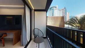 A balcony with a TV, a chair, and a desk. - Nomah - Aptos por Temporada na Vila Nova Conceição (São Paulo)