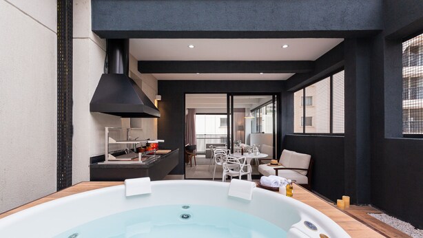 A modern indoor pool area with a hot tub, seating, and a view of the outside balcony. - Nomah - Aptos por Temporada na Vila Nova Conceição (São Paulo)