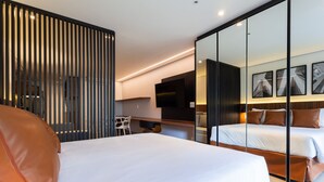 A modern hotel room with a large bed, a desk, and a seating area. - Nomah - Aptos por Temporada na Vila Nova Conceição (São Paulo)