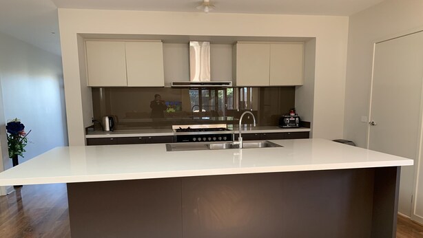 A modern kitchen with a large island, stainless steel appliances, and dark cabinetry.