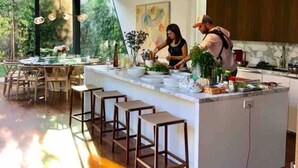 Une cuisine moderne dotée d’un îlot central, de tabourets de bar et de grandes fenêtres.
