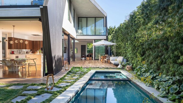 Une maison moderne dotée d’une piscine, d’un coin repas et d’une terrasse.