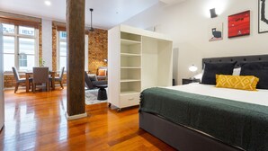 A modern bedroom with a large bed, a wardrobe, and a dining area with a table and chairs. - Toodle's Characterful loft on Lorne Street (Auckland)