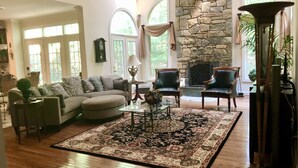 A spacious living room with a stone fireplace, a large rug, and leather armchairs. - Gorgeous, Wooded 3 Acre Estate -5 Bed/4  Bath-Leesburg/Brambleton/Aldie area (Leesburg)