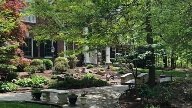 A stone pathway leading to a house with a brick facade, surrounded by lush greenery and a well-maintained garden. - Gorgeous, Wooded 3 Acre Estate -5 Bed/4  Bath-Leesburg/Brambleton/Aldie area (Leesburg)