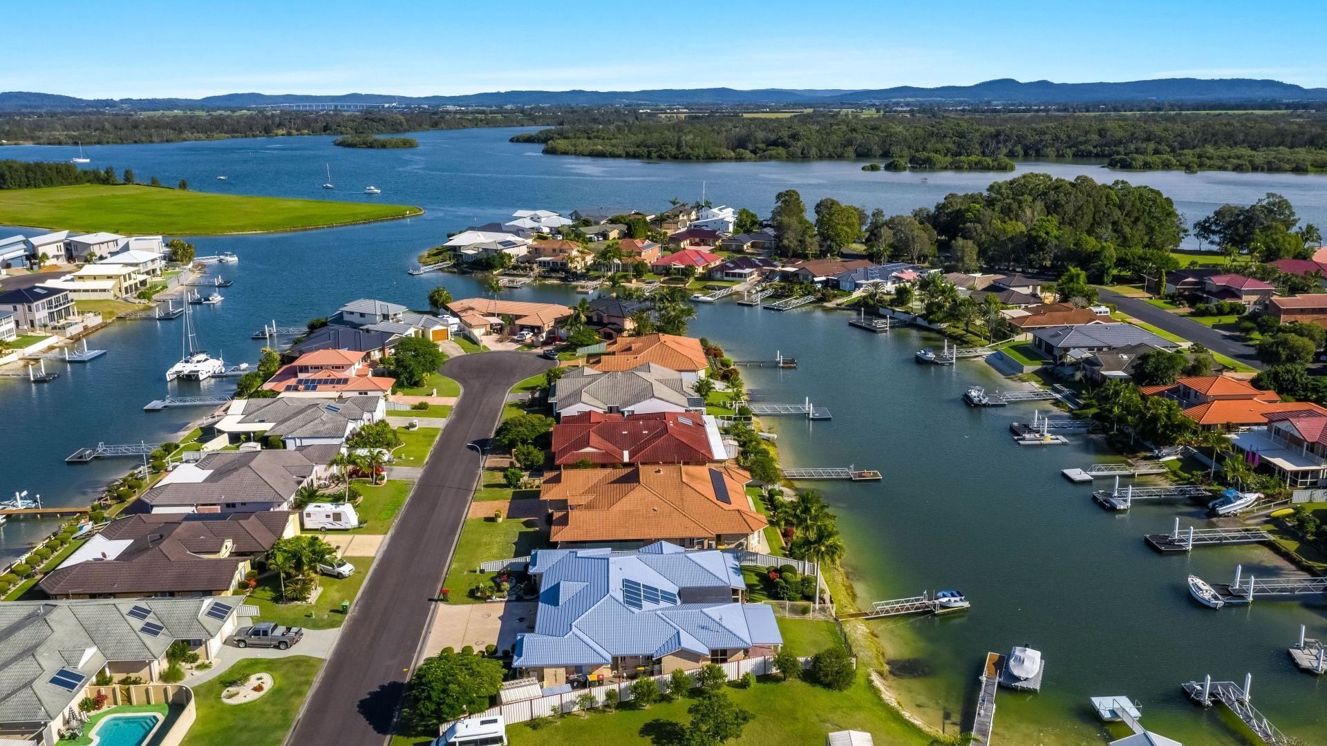 Un quartier résidentiel avec des maisons, une route et un port de plaisance où sont amarrés des bateaux.