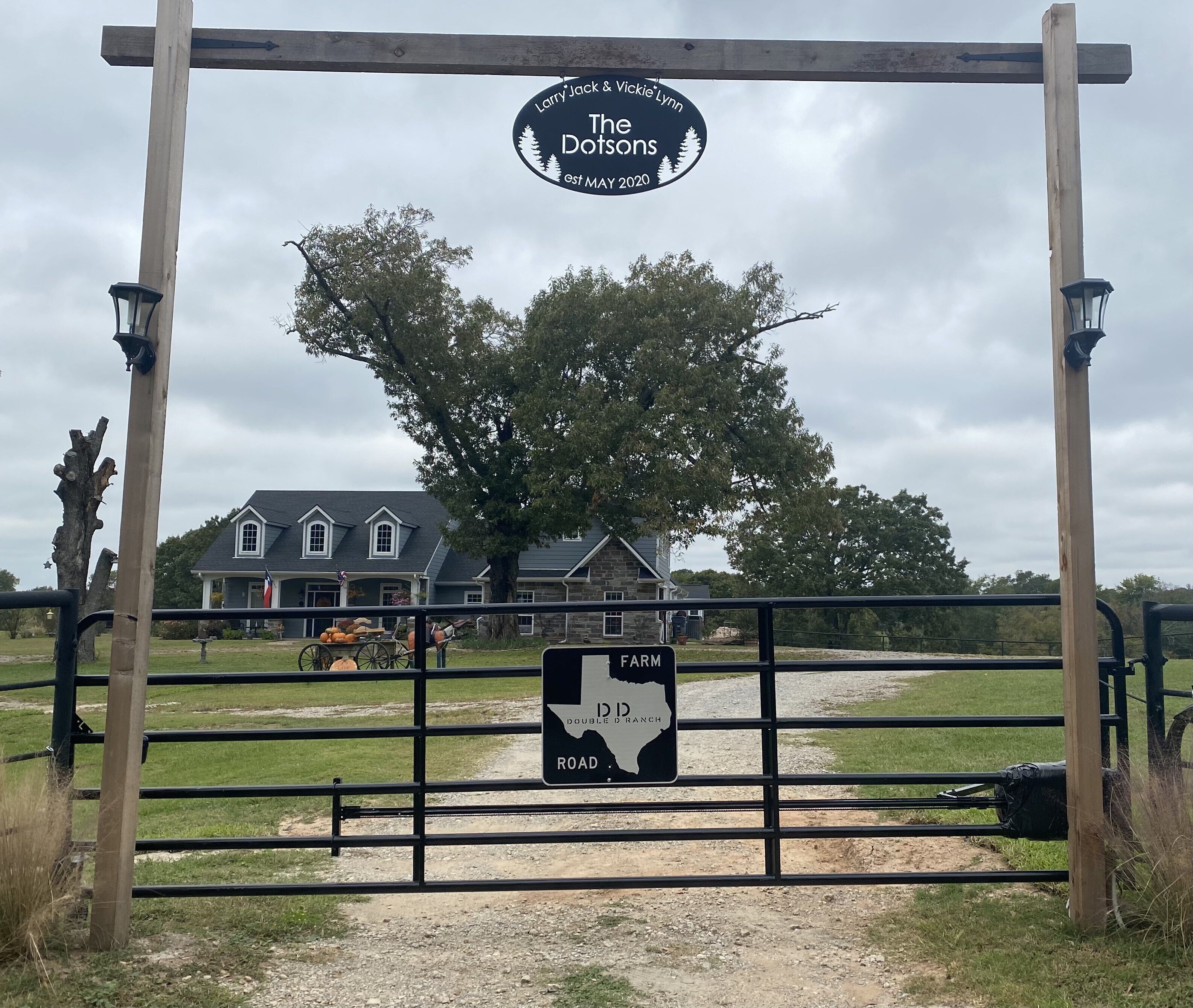 A farm gate with a sign for 'The Dotsons' and a 'Double D Ranch Road' sign.