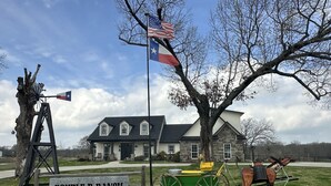 A historical site with a sign reading "DOUBLE D RANCH," a windmill, a horse-drawn carriage, and a house with a stone facade. - Double D Ranch Guest House (Emory)