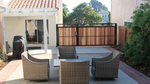 An outdoor patio with wicker furniture and a tiled floor.